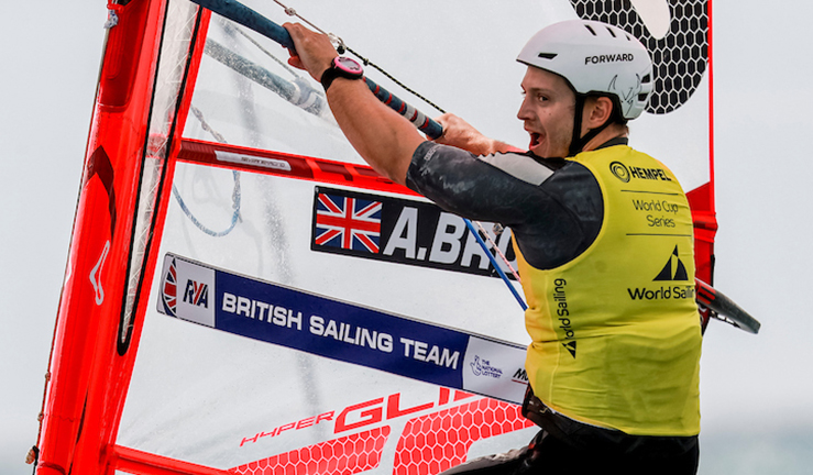 Windsurfer Andy Brown wearing the gold bib while crossing the finish line on his IQ Foil board