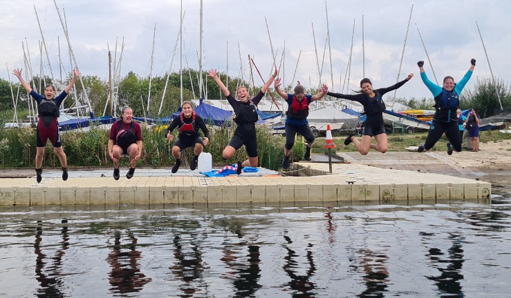 Women in wetsuits jumping off a pontoon into the water