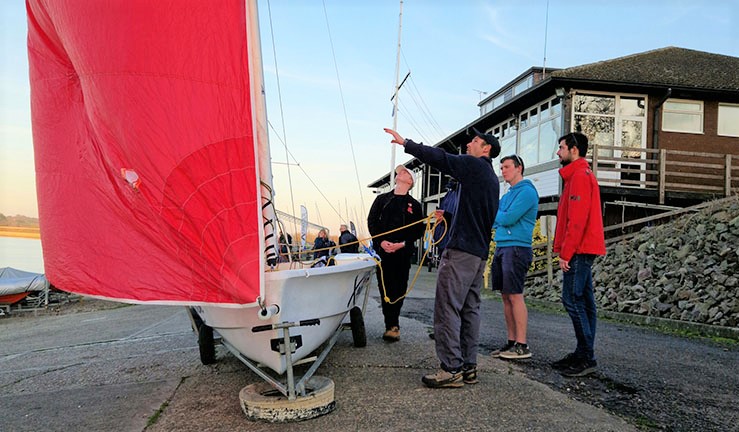 Instructor and RYA Advanced Dinghy Instructor course participants on the patio at DWSC learning about spinnakers on a rigged boat.