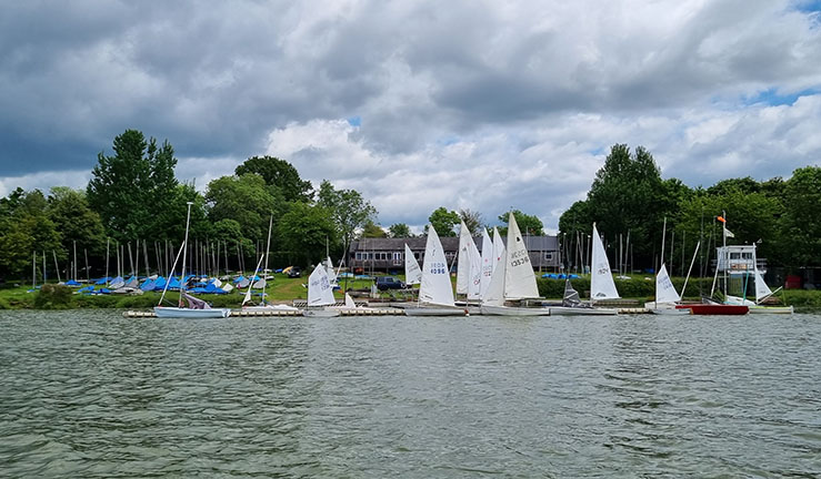 View from the water of Banbury Sailing Club and boats with sails up.