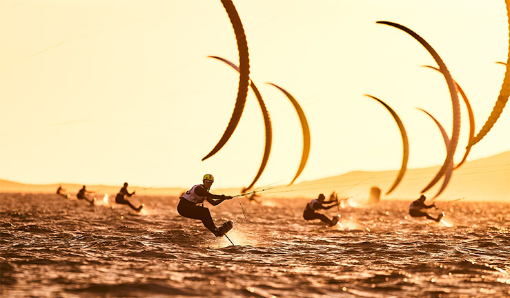 wide shot of  kite foilers sailings in the sunset just after golden hour