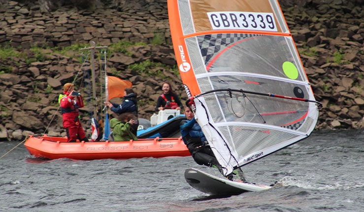 Two junior sailors sat on a boat on shore with smiles and thumbs up!