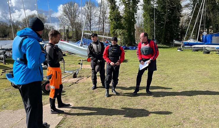 Group of people taking part in an RYA Dinghy Instructor course at Shropshire SC, on shore listening to a briefing.