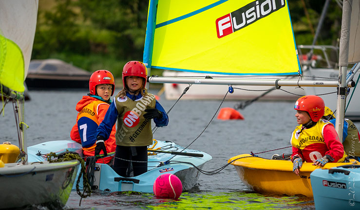 Three young sailors having fun on the water with boats and a ball with the OnBoard Fleet at the 2022 BYS Regional Junior Championships.