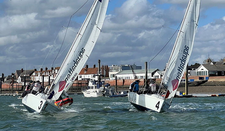 Two teams match racing in 707 keelboats with Royal Corinthian Yacht Club, Burnham on Crouch, in the background.