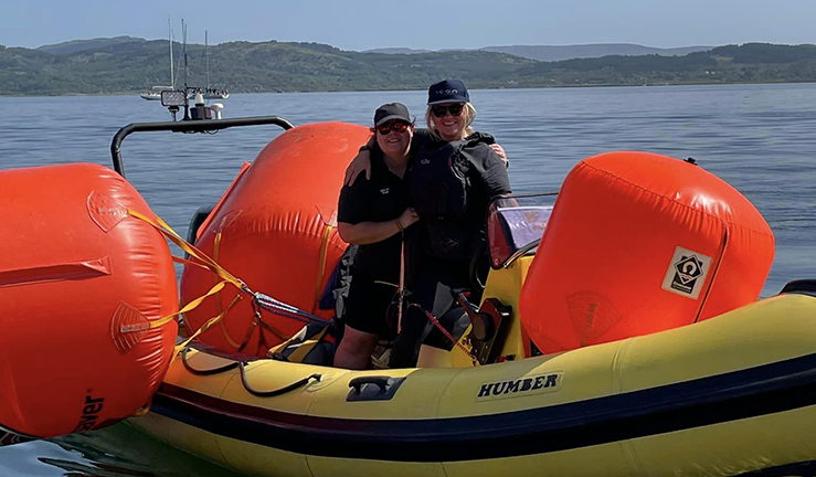 Women helping lay race buoys onboard inflatable power boats on a Scottish Loch in the sunshine.