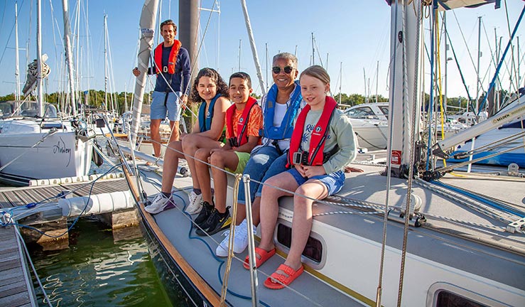 posed shot of family sitting on top if sailing yacht