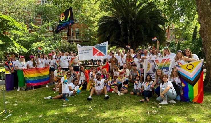 A group of people are gathered on grass at Pride London.