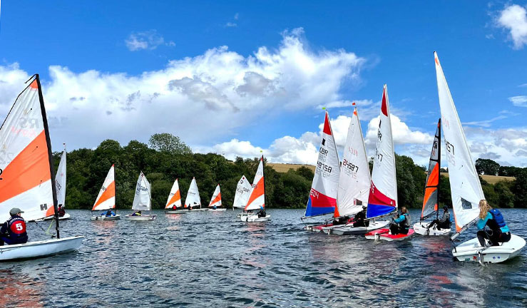 Junior boats with colourful sails up on shore waiting to launch at Bassenthwaite for the BYS North Regional Junior Championships 2023