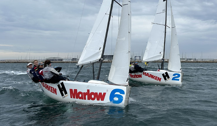 Two teams match racing Elliot 6m keelboats upwind on a grey day with WPNSA in the background, at the 2023 RYA Marlow Ropes Women's Match Racing Championships.