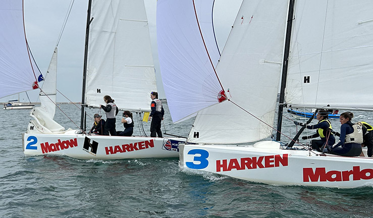 Two teams match racing Elliot 6m keelboats downwind with spinnakers flying on a grey day in Portland Harbour at the 2023 RYA Marlow Ropes Women's Match Racing Championships.