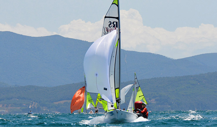 Teenagers Ben Greenhalgh and Tom Sinfield from Port Dinorwic Sailing Club sending it downwind with the kite flying on the sea and in the sunshine at the 2023 RS Feva Worlds in Italy.