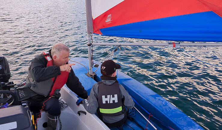 Volunteer coach sits in a rib talking with a topper sailor.