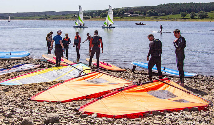 Lots of people having fun in the sun on shore in front of the clubhosue at Derwent Reservoir Sailing Club open day.