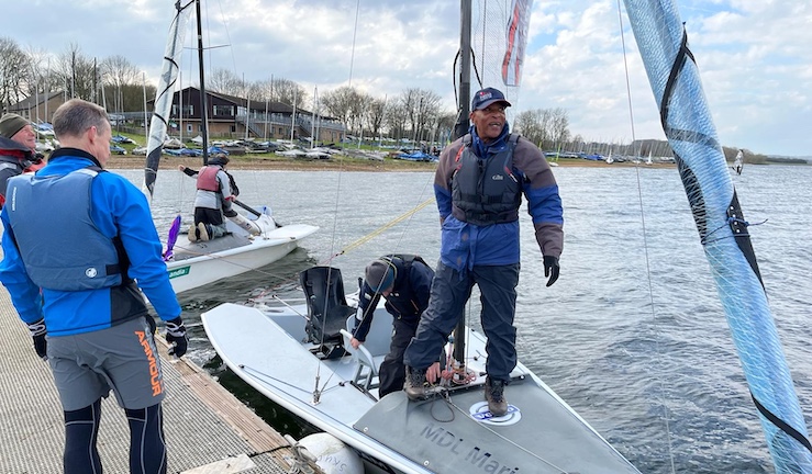 Half a dozen people rigging two keelboats on the pontoon at Rutland SC for the Regional Training Day with the clubhouse in the background.